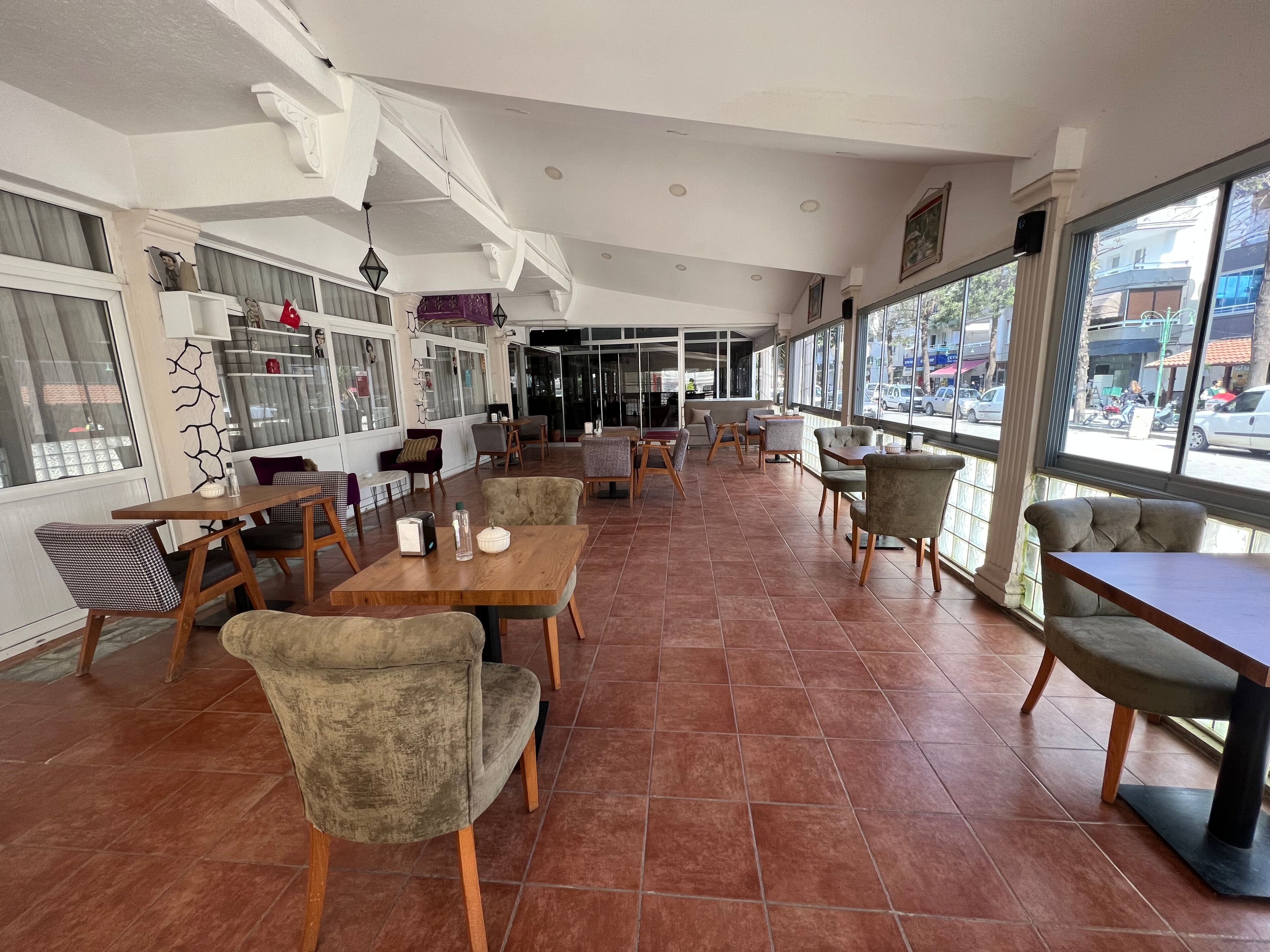 A spacious cafe with multiple seating areas, including tables and chairs, and large windows offering views of the street.