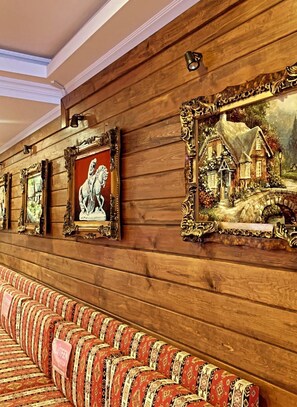 A row of framed artworks on a wooden wall, a patterned bench in the foreground, and a ceiling with recessed lighting. - Hotel Cenka Ephesus (Selçuk)