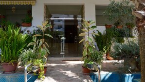 Un patio con plantas en macetas, una puerta de cristal y un piso de baldosas.
