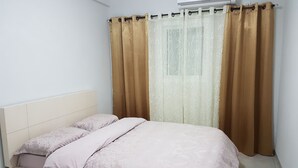A bedroom with a bed, beige curtains, and an air conditioning unit. - Comfort Apartments (Haifa)
