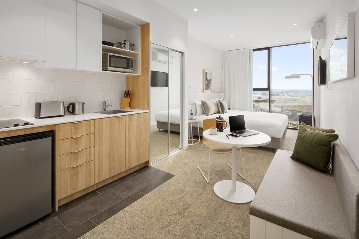 Quarto de hotel moderno com cozinha, área de refeições e sofá com vista.