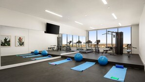 A modern gym with exercise equipment, large windows, and blue mats. - Quest Epping (Epping)