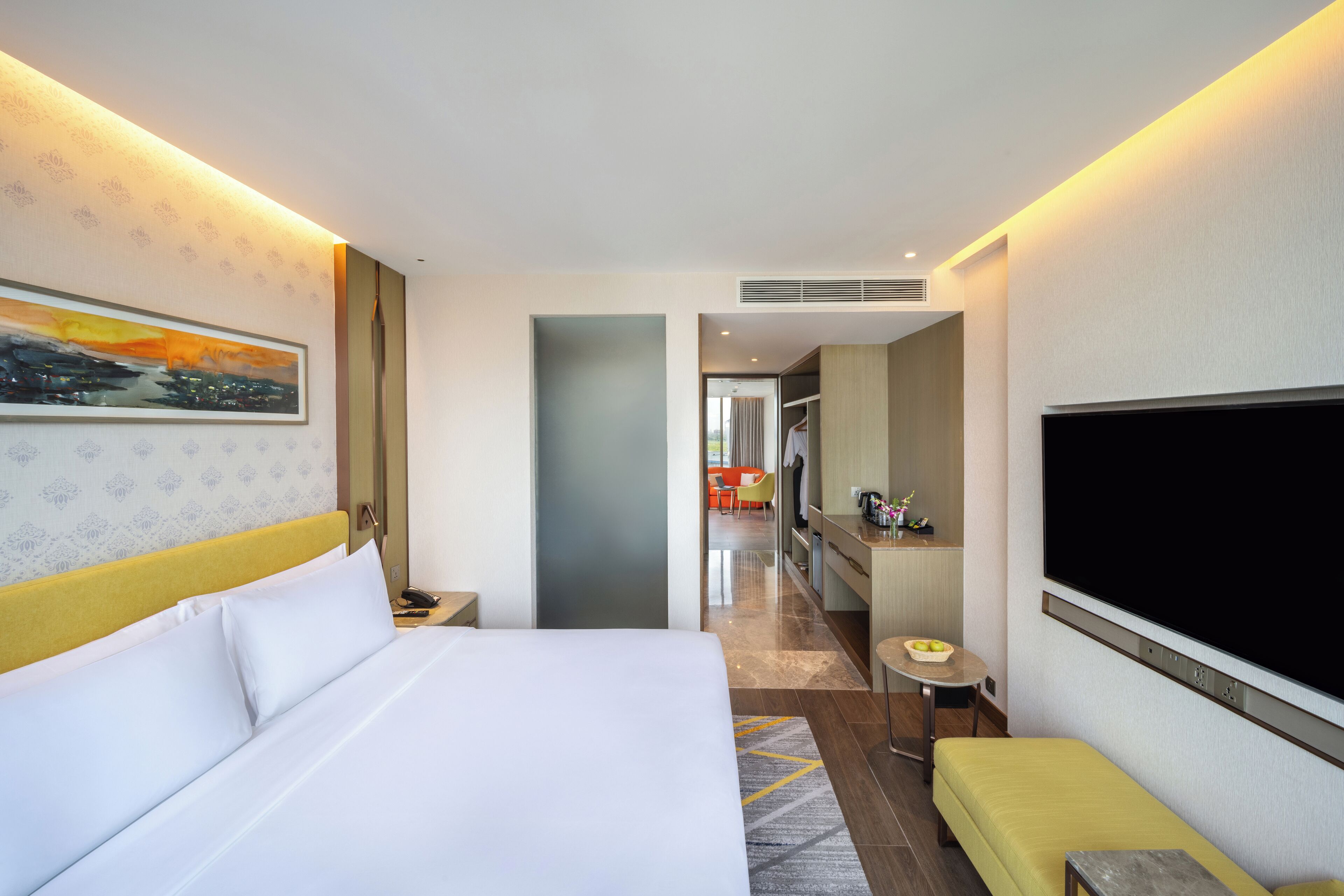 A hotel room with a bed, a TV, a seating area, and a kitchenette.