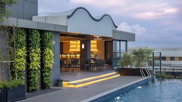 Un edificio moderno con piscina, mobiliario exterior y jardines verticales.