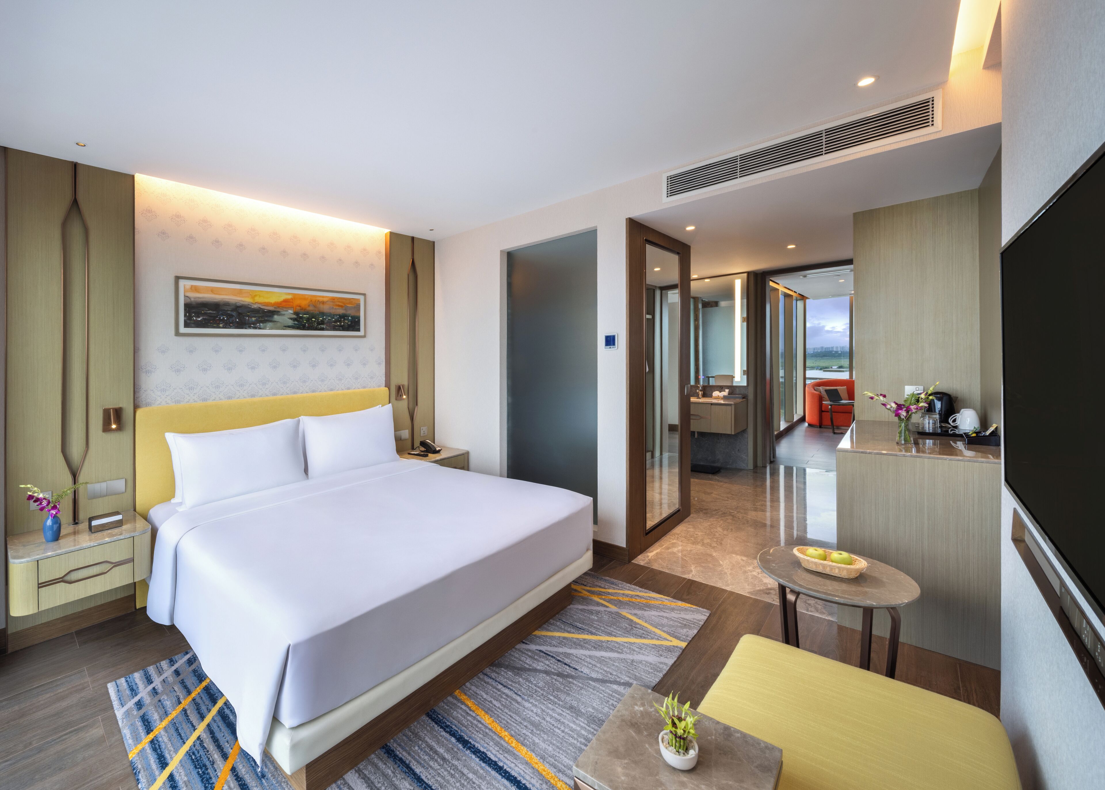 Une chambre d’hôtel moderne dotée d’un grand lit, d’un bureau, d’une salle de bain et offrant une vue sur la ville.