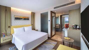Une chambre d’hôtel moderne dotée d’un grand lit, d’un bureau, d’une salle de bain et offrant une vue sur la ville.