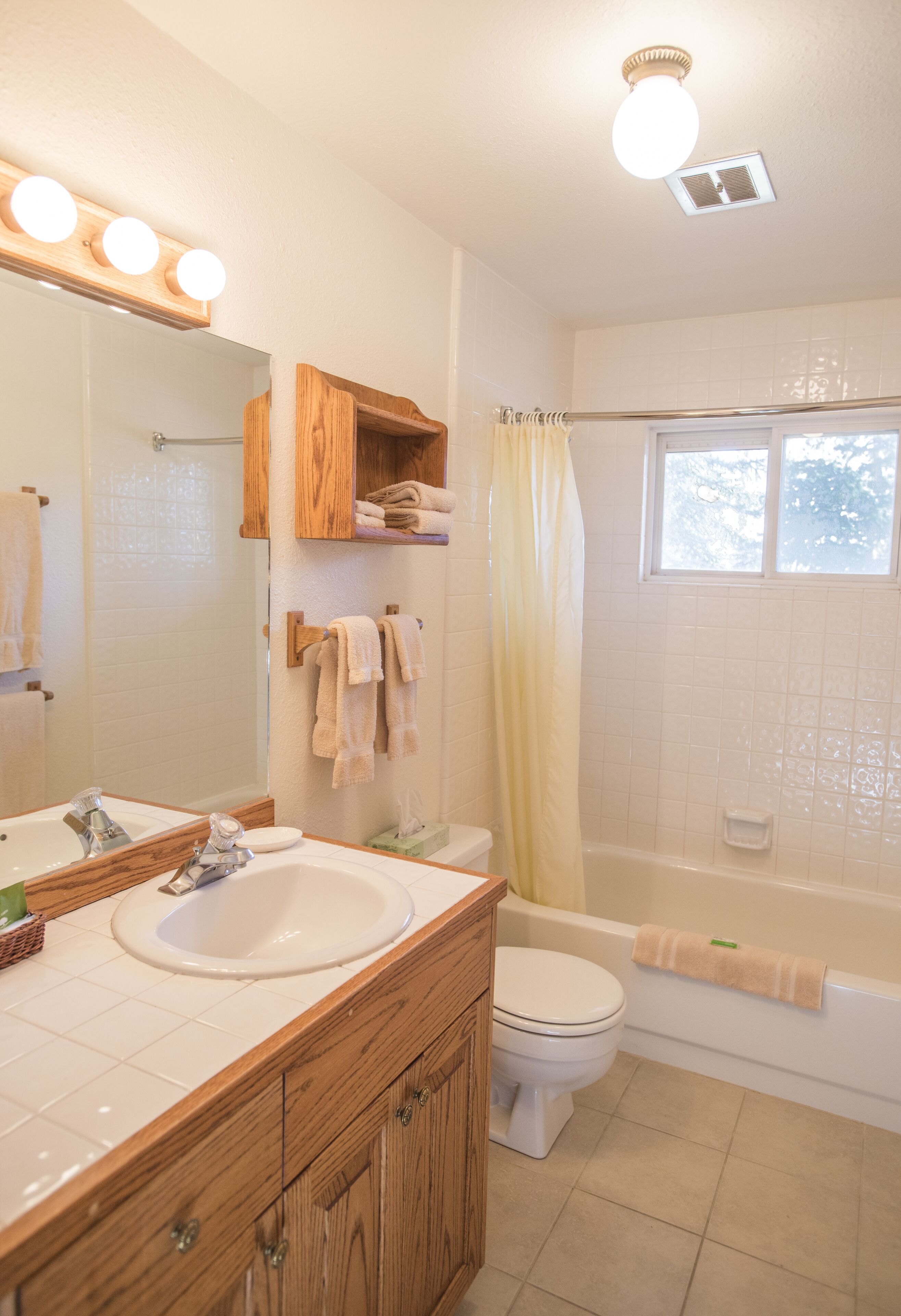 Een badkamer met een wastafel, spiegel, wastafelmeubel, toilet en bad.