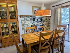 A dining area with a stone fireplace, wooden chairs, and a table. - Large and spacious 2 bedroom residence. This is the best location in Ketchum! (Ketchum)