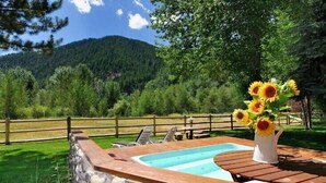 A pool area with a stone wall, wooden deck, and a vase of sunflowers.