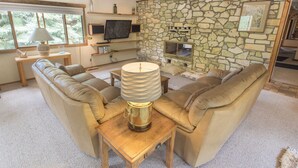 A cozy living room with a stone wall, leather sofa, wooden coffee table, and a television.