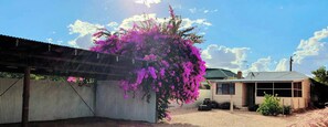 A church cottage stay with a rear courtyard, corrugated metal fence, and a small building with a sloped roof. - Outback Church Cottage  (Broken Hill)