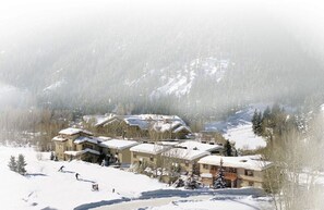 Une station de ski enneigée, dotée de plusieurs bâtiments, de pistes de ski et offrant un paysage montagneux en toile de fond.