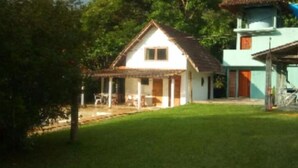 A house with a thatched roof, a porch, and a small garden. - Acomodação Penedo (Itatiaia)