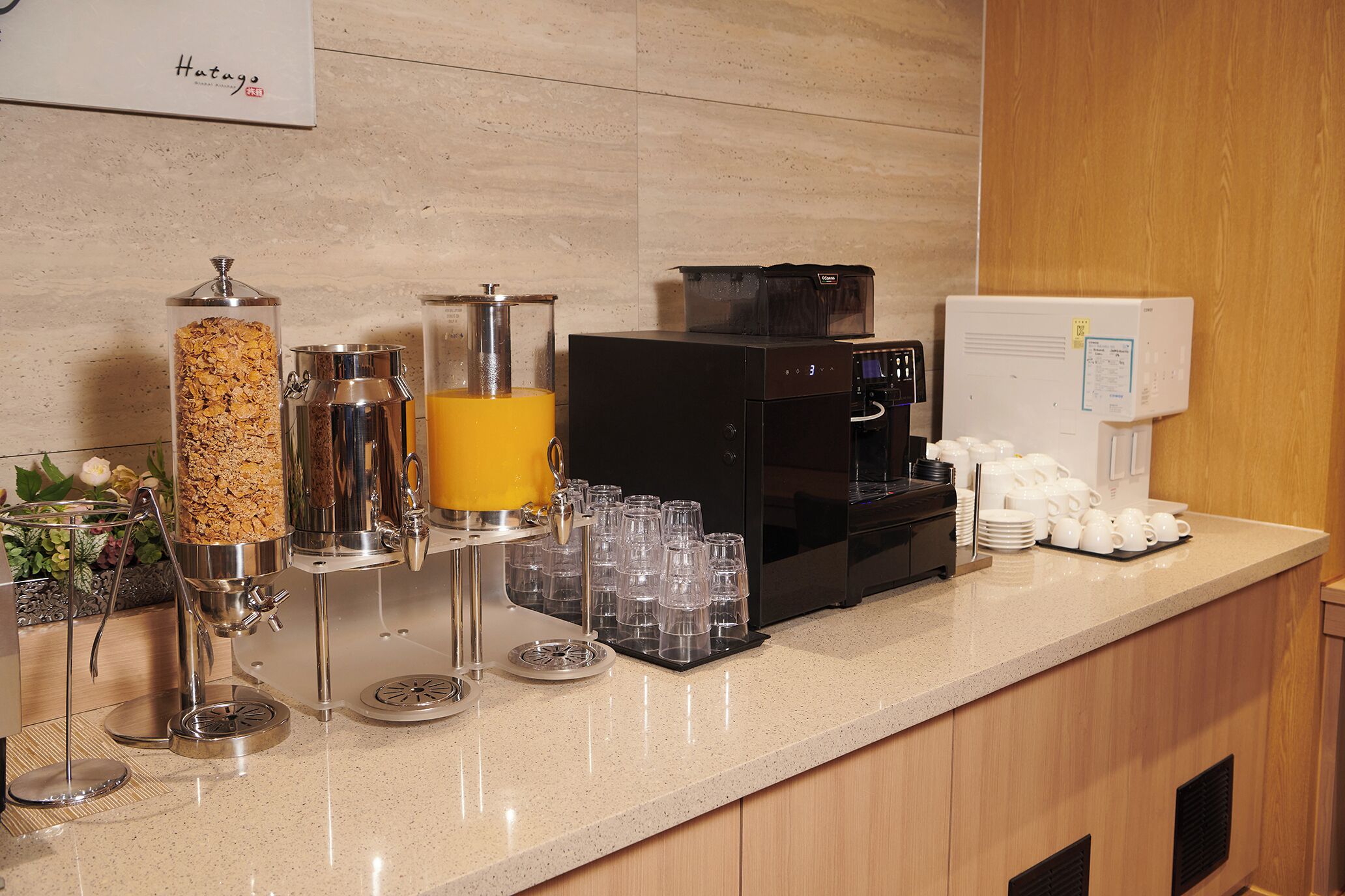 Una barra de desayuno con una máquina de café, un dispensador de zumo y un dispensador de cereales.