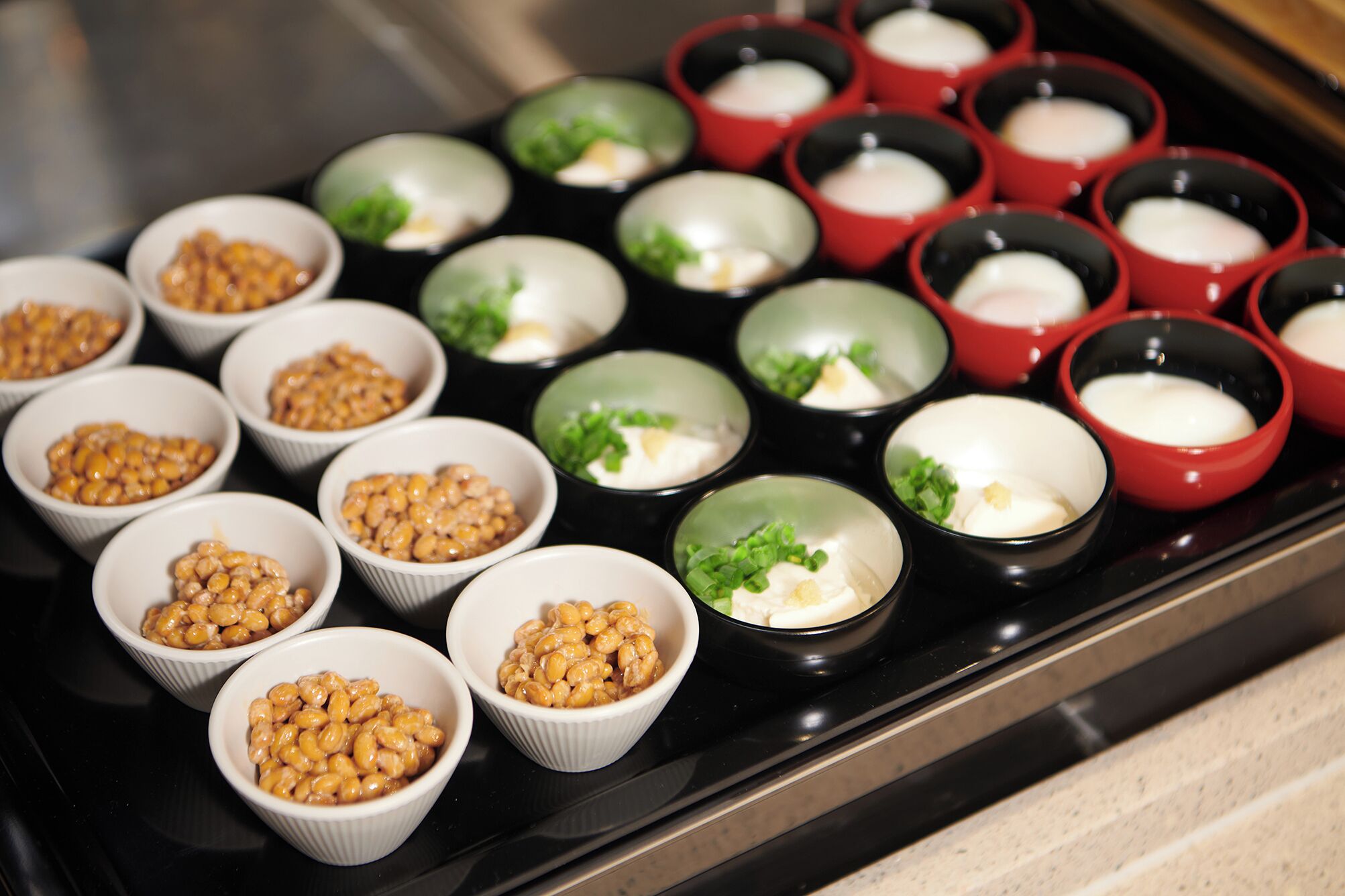 Verschillende kommen met diverse soorten eten, gerangschikt op een zwart aanrecht.