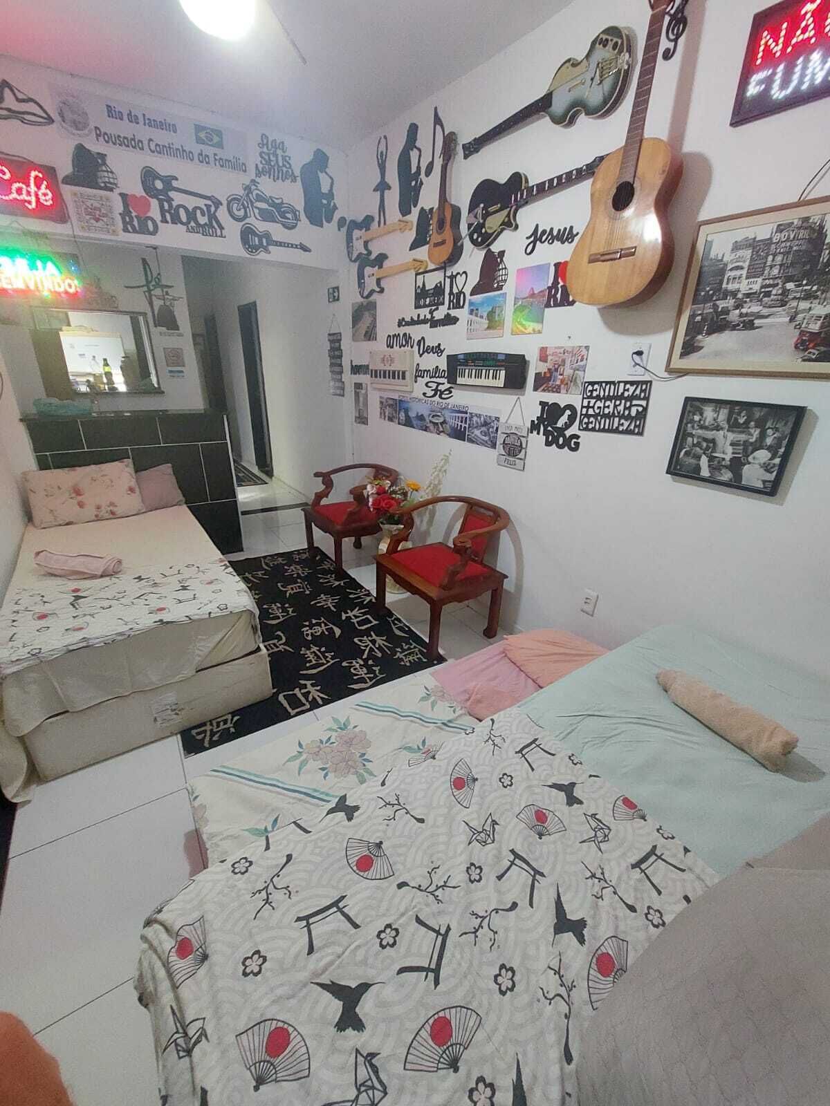 Quarto com duas camas, um espelho e vários cartazes e quadros nas paredes.
