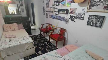Quarto com duas camas, um espelho e vários cartazes e quadros nas paredes.
