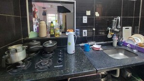 A kitchen with a gas stove, pots, a sink, and various kitchen items. - Pousada Cantinho da Familia (Rio de Janeiro)