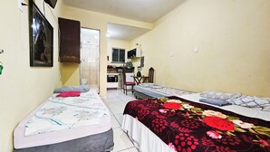 A small, compact room with two single beds, a desk, and a chair. There is a window and a door leading to a bathroom. - Pousada Cantinho da Familia (Rio de Janeiro)