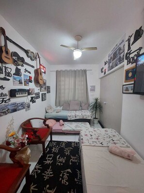 A bedroom with two beds, a ceiling fan, and various wall decorations including guitars and framed photos. - Pousada Cantinho da Familia (Rio de Janeiro)
