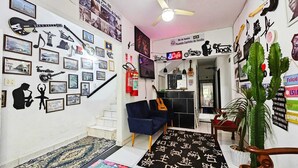 A living room with a staircase, a blue sofa, a guitar, and a cactus plant. - Pousada Cantinho da Familia (Rio de Janeiro)