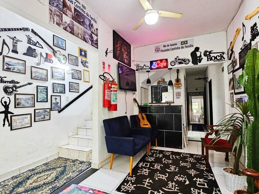 A living room with a staircase, a blue sofa, a guitar, and a cactus plant.