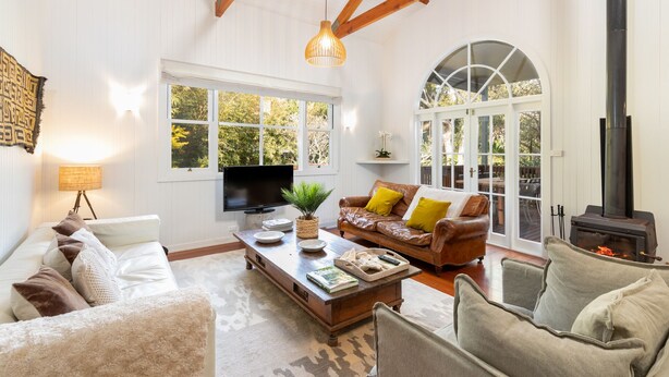A spacious living room with a fireplace, large windows, and a cozy seating area. - Luxurious Jetty House, Coffs Harbour – privacy & tranquility (Coffs Harbour)