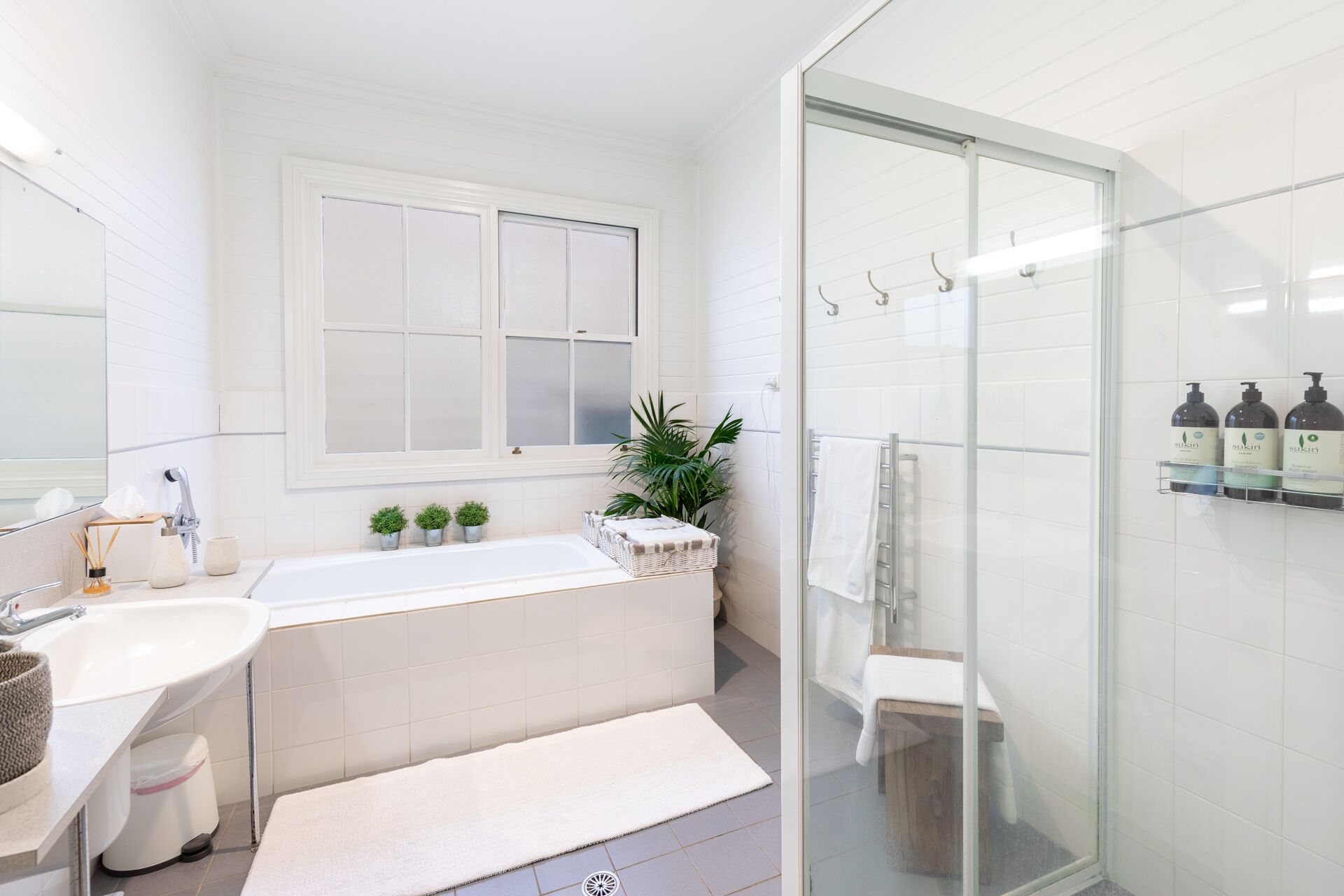 A modern bathroom with a bathtub, a glass shower enclosure, and a large window.