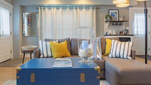 A living room with a blue chest of drawers, a glass vase with seashells, and a sofa with patterned cushions. - Superb Location! 5min walk to town & EV charger port (Camden)