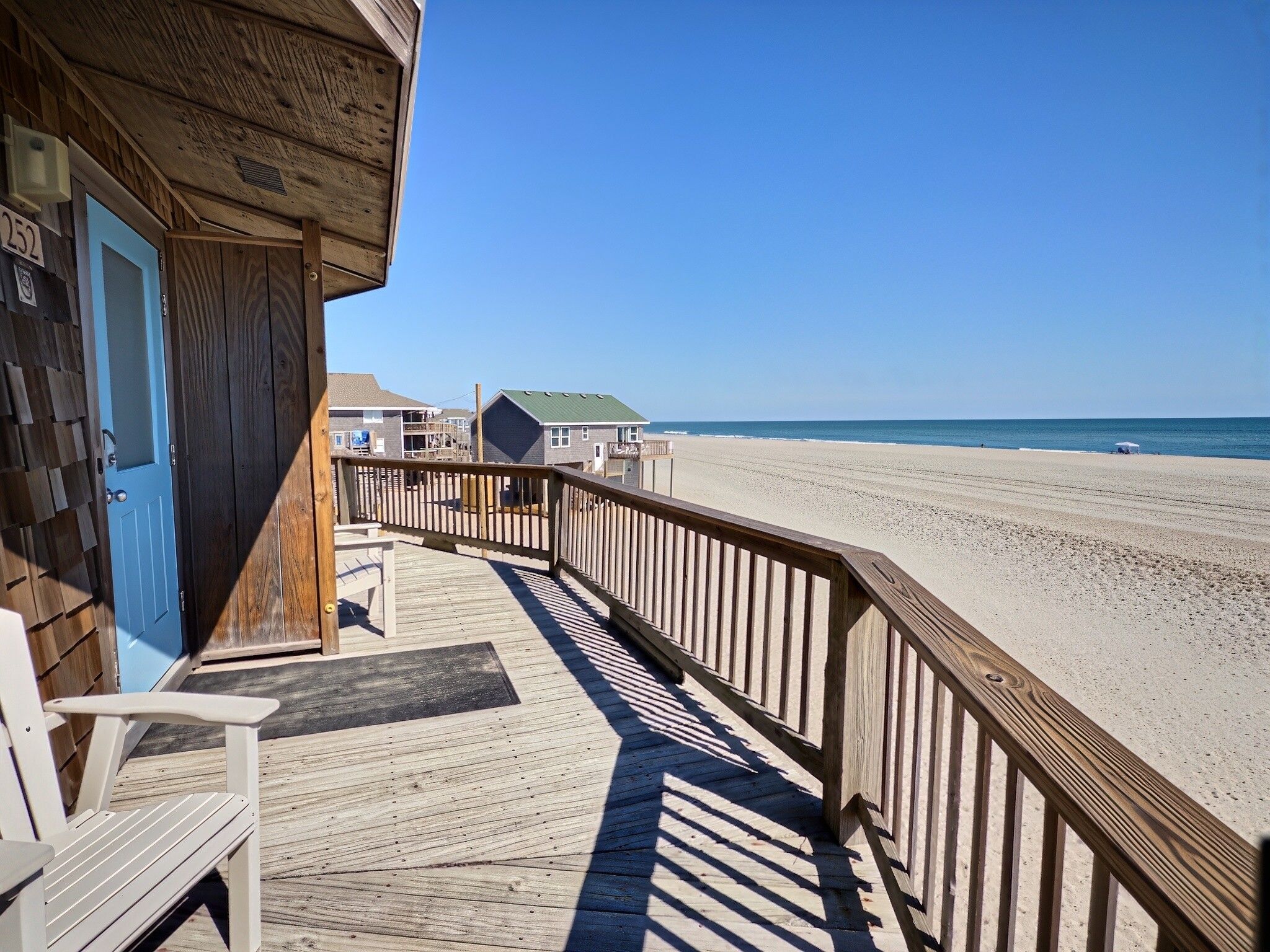 A wooden deck with a view of the beach and ocean.