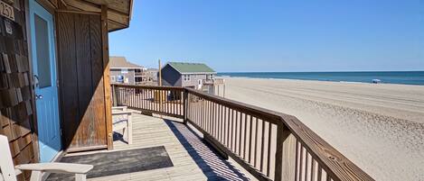 A wooden deck with a view of the beach and ocean.