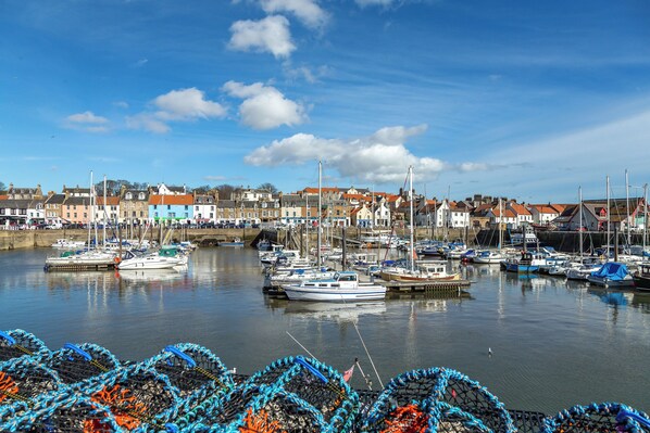 A harbor with boats docked, a bridge, and buildings in the background.