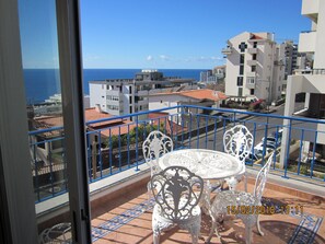 Enjoy breathtaking views of the sea from this balcony with a table and chairs.