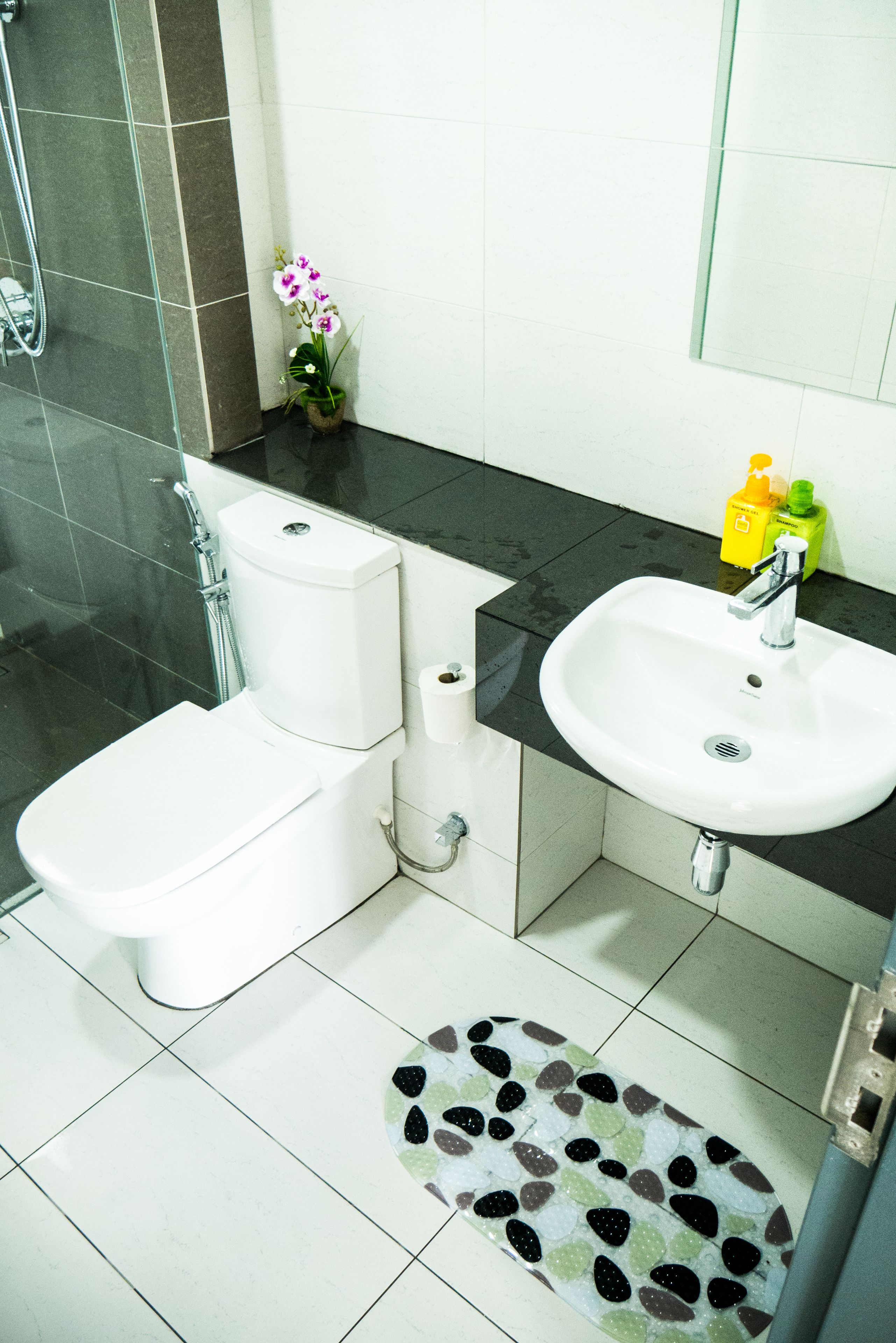 A bathroom with a toilet, bidet, sink, and a small potted orchid.