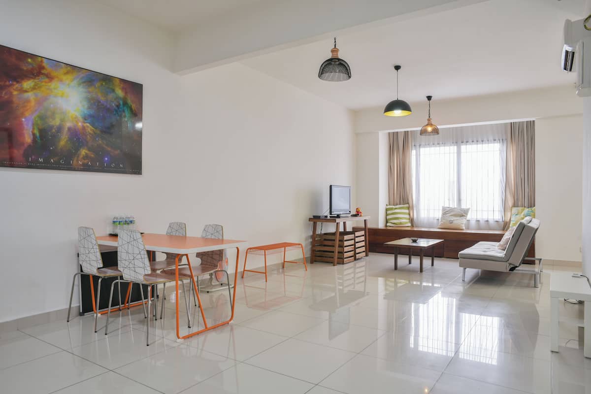 Una sala de estar moderna con comedor, un cuadro abstracto grande y un televisor.