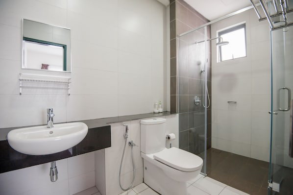 A modern bathroom with a white sink, toilet, and glass-enclosed shower.