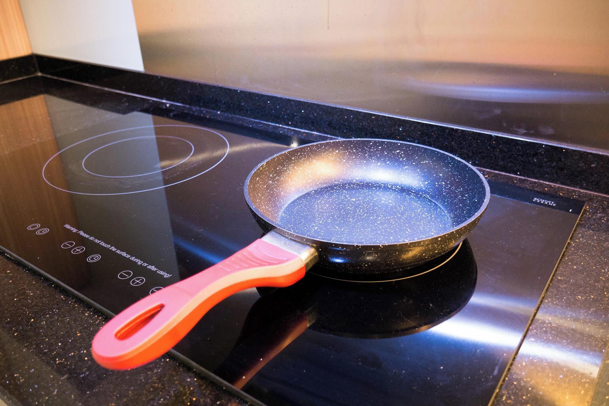 A frying pan with a red handle on an induction cooktop.