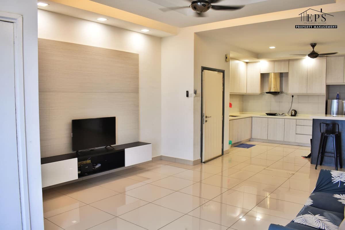 Una sala de estar moderna con un televisor de pantalla plana, un sofá y una cocina con un taburete de bar.