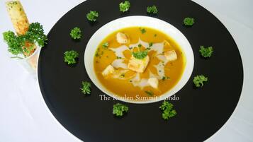 Un tazón de sopa con crutones y perejil sobre un plato negro.
