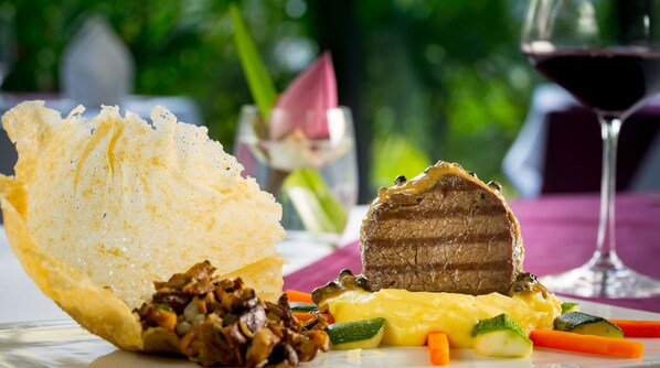 A plate with a piece of meat, vegetables, and a bread-like item.