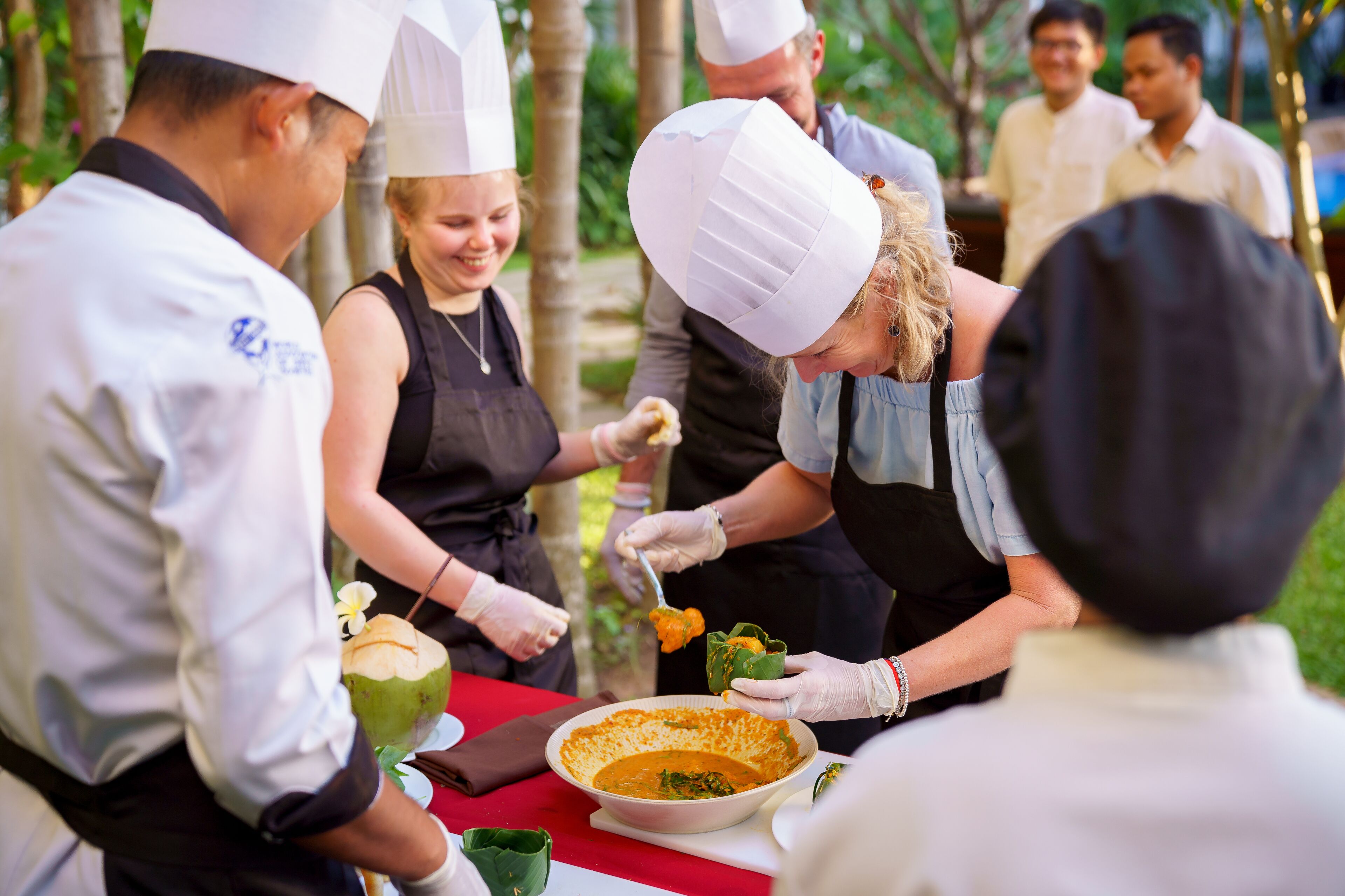 Un grupo de personas con gorros de chef sirviendo comida en un evento al aire libre.