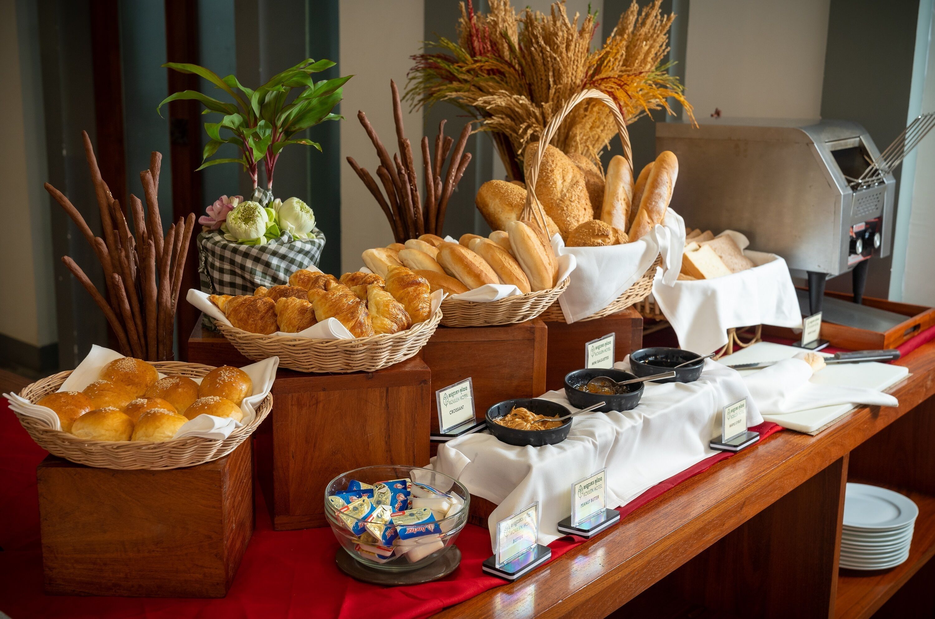 Uma mesa de buffet com pães, doces e acompanhamentos variados.