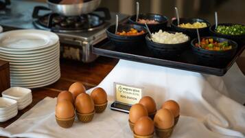 A buffet setup with various food items and a sign indicating an egg station.