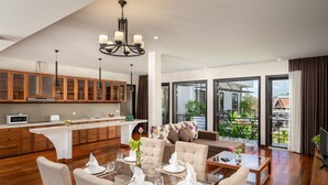 A modern kitchen with wooden cabinets, a central island, and a dining area with a glass table set for four.