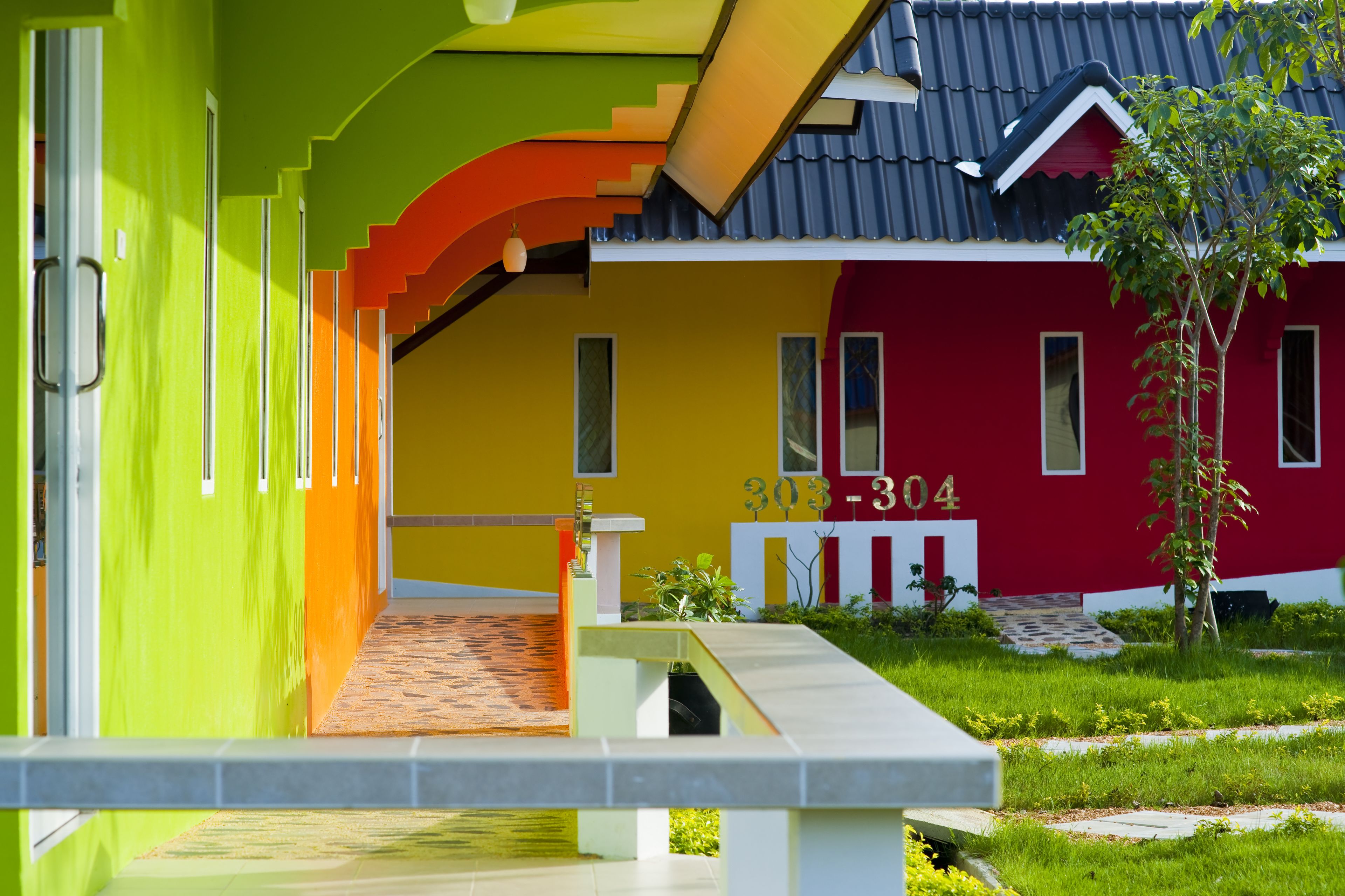 Un edificio colorido con fachada roja y amarilla, una escalera y un pequeño jardín.