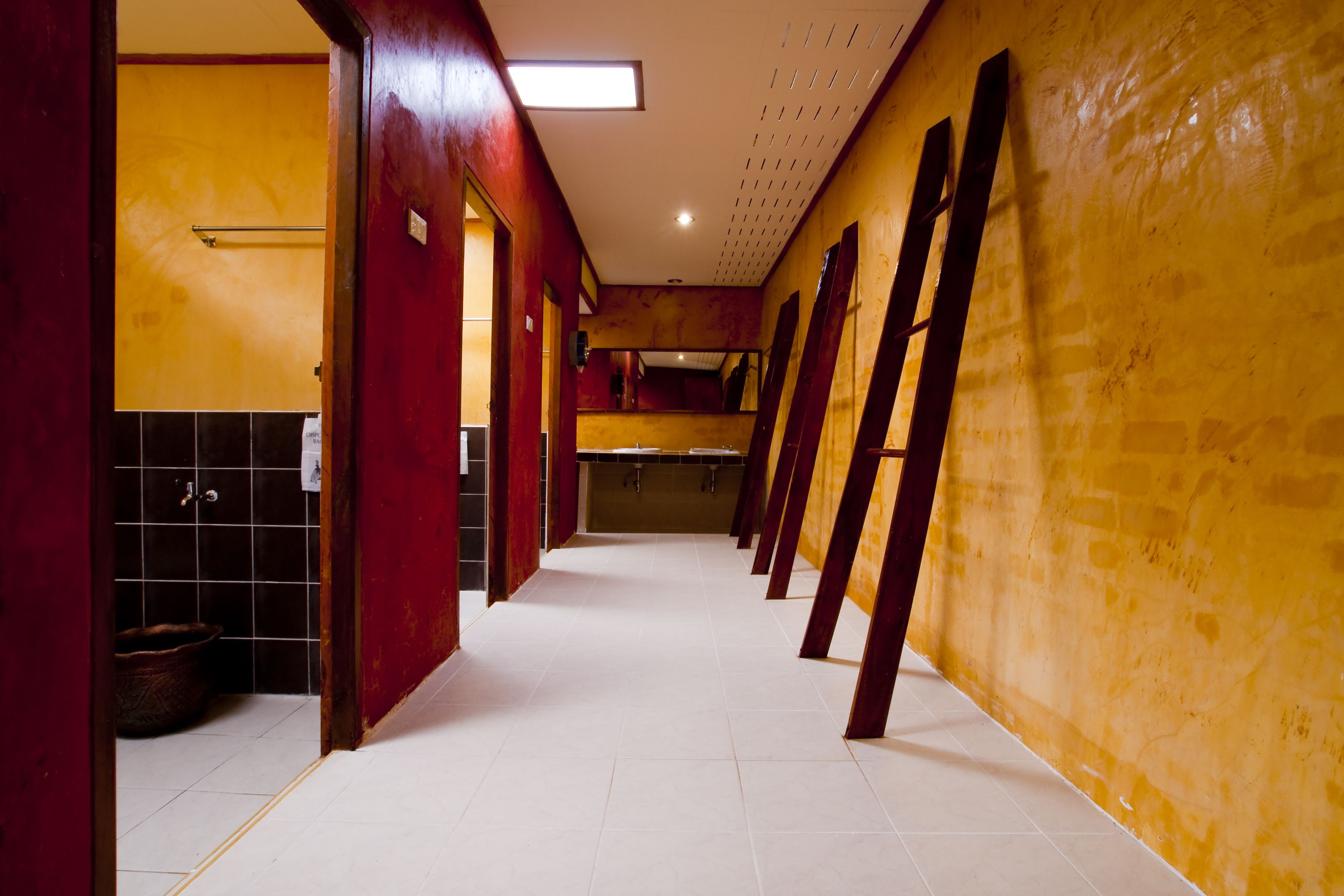 A long, narrow hallway with tiled floors and walls painted in yellow and red.