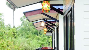 A covered outdoor seating area with wooden benches and a colorful hanging light fixture. - Lampam Resort (Phatthalung)