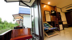 A modern room with a large window, a wooden bench, a colorful cushion, and a small table. - Lampam Resort (Phatthalung)
