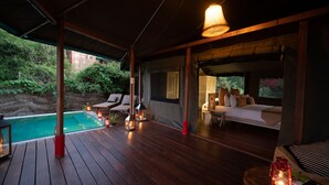 A wooden deck with a pool, outdoor seating, and a bed with pillows. - Flameback Eco Lodge (Weerawila)