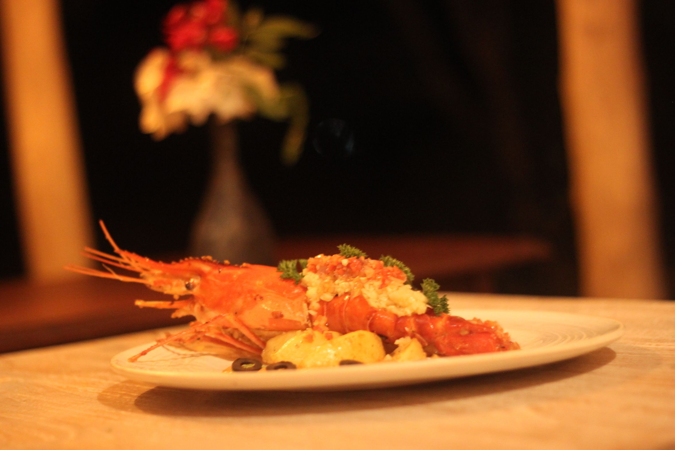 A plate of food with shrimp and vegetables on a table.